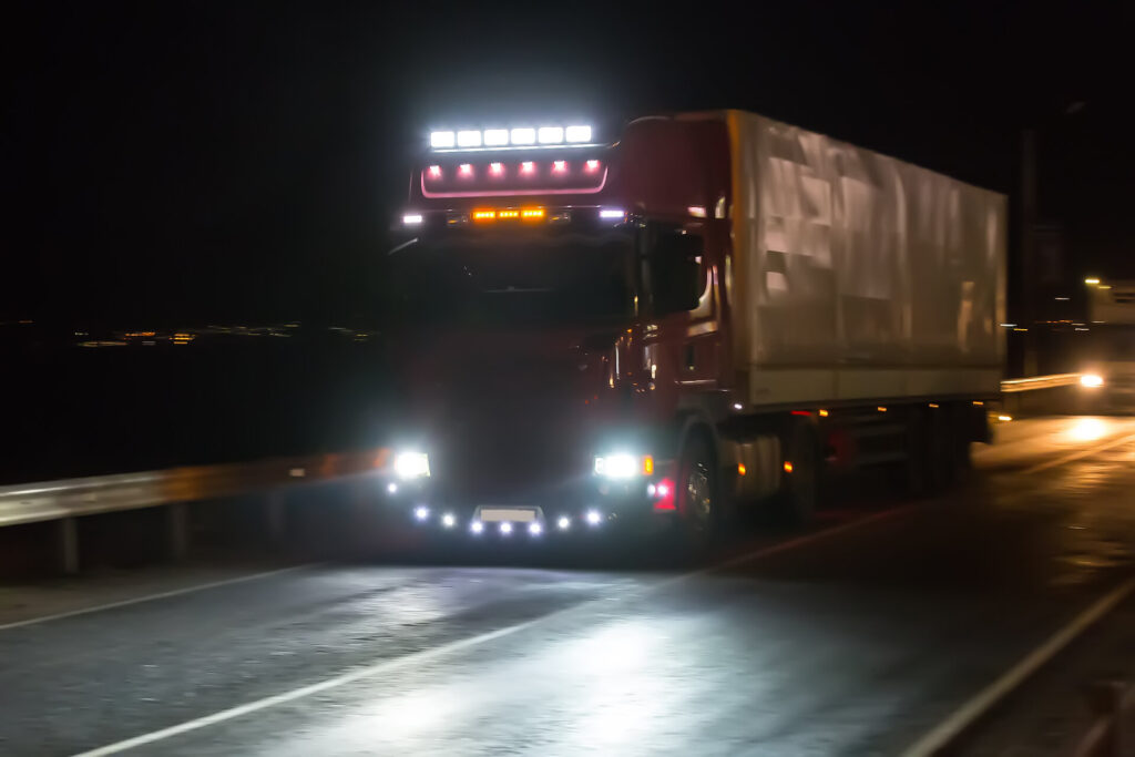 Fahrender LKW mit eingeschalteter Beleuchtung bei Nacht