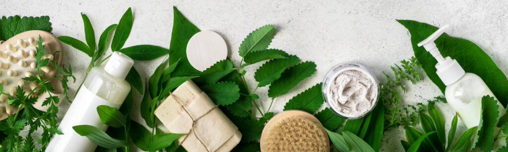Naturkosmetik und grüne Blätter, natürliche Bio-Hautpflegeprodukte auf weißem Steinhintergrund.